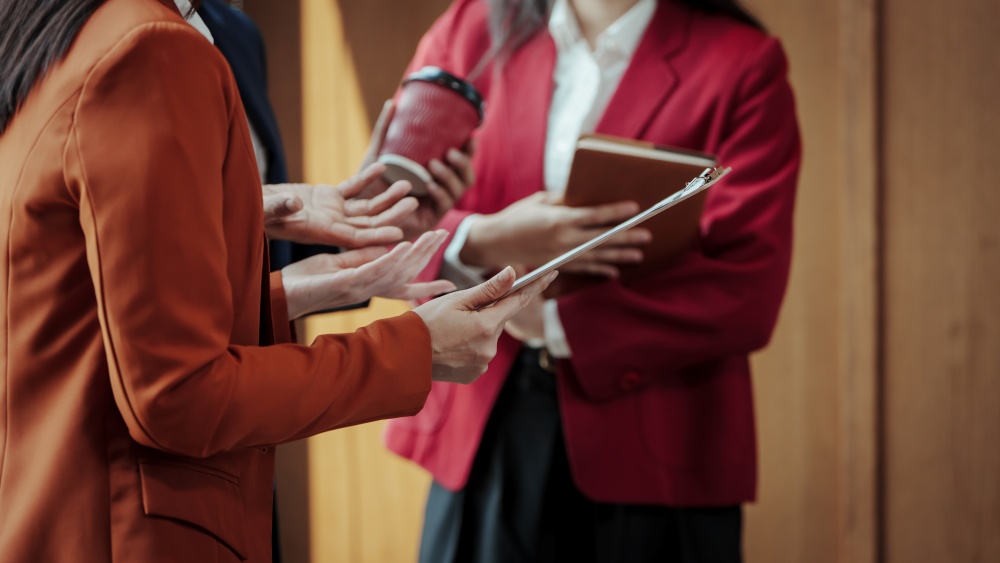 Two people discuss work while holding a tablet.